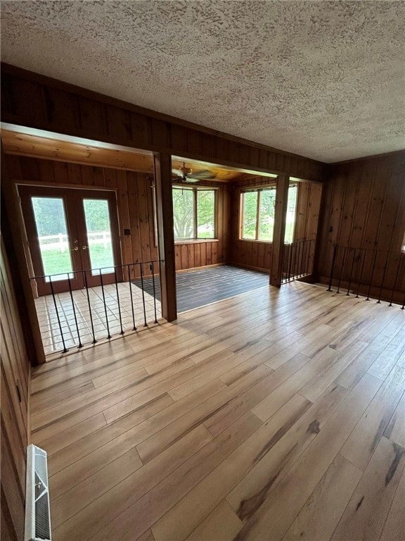 192 Yellow Creek Rd, Lancaster Twp, PA 16037 - empty room featuring french doors, wood finished floors, a textured ceiling, wooden walls, and plenty of natural light