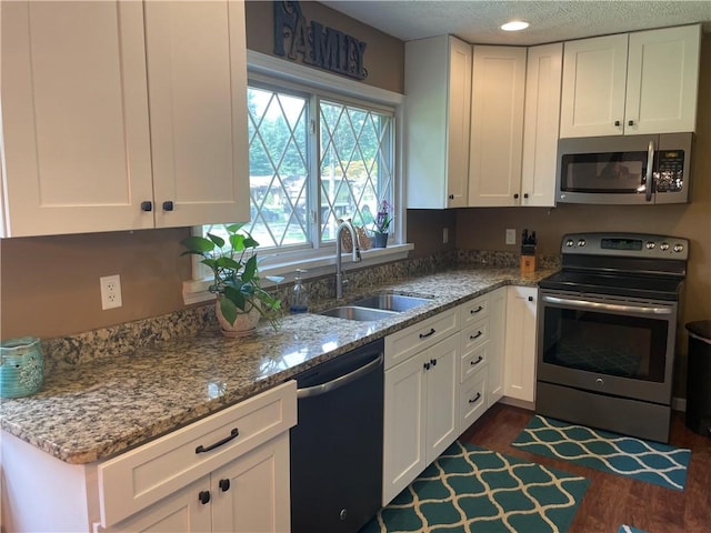 17 Evergreen, Hempfield Twp, PA 16125 - kitchen featuring appliances with stainless steel finishes, white cabinets, light stone countertops, dark wood-style flooring, and a textured ceiling