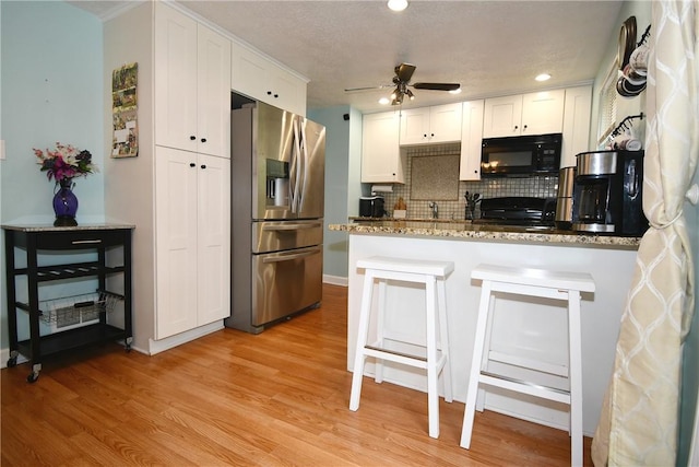 4095 Overlook St, South Park, PA 15129 - kitchen with stainless steel fridge with ice dispenser, black microwave, white cabinetry, ceiling fan, and tasteful backsplash