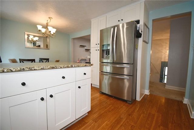 4095 Overlook St, South Park, PA 15129 - kitchen with stainless steel fridge, a chandelier, white cabinets, wood finished floors, and light stone counters