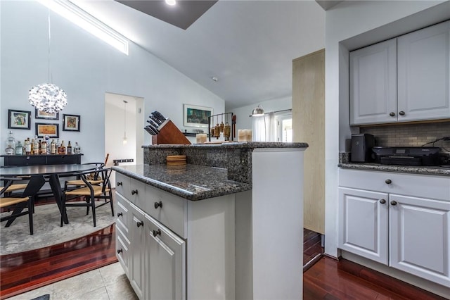 2207 Kenzie Dr, Robinson Twp, PA 15205 - kitchen featuring lofted ceiling, dark stone counters, decorative backsplash, a center island, and dark wood finished floors