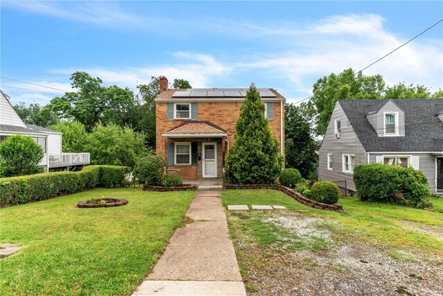 3405 Willett Rd, Baldwin Boro, PA 15227 - view of front of home with roof mounted solar panels, a front lawn, brick siding, and a chimney