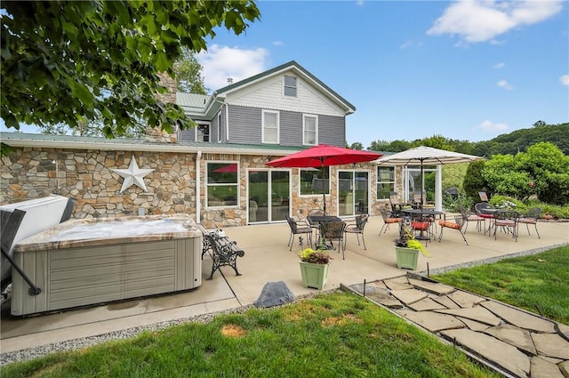160 Railroad St, Hempfield Twp, PA 15665 - back of house featuring a hot tub, stone siding, a patio area, and a lawn