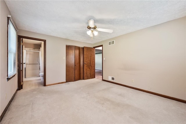 1222 Lakevue Dr, Penn Twp, PA 16002 - unfurnished bedroom with light carpet, a textured ceiling, a closet, connected bathroom, and ceiling fan
