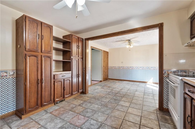 1222 Lakevue Dr, Penn Twp, PA 16002 - kitchen with a ceiling fan, white range with electric stovetop, a wainscoted wall, open shelves, and light stone finish flooring