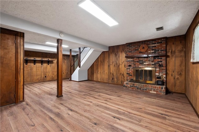 1222 Lakevue Dr, Penn Twp, PA 16002 - unfurnished living room with wooden walls, wood finished floors, a textured ceiling, stairs, and a fireplace