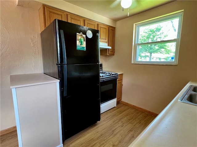 3329 Recker Dr, Baldwin Boro, PA 15227 - kitchen with range with gas stovetop, freestanding refrigerator, under cabinet range hood, light wood-style floors, and light countertops