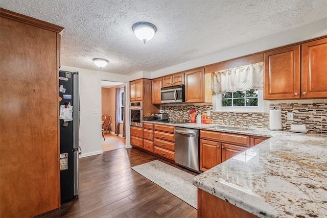 27 Watson St, Leet Twp, PA 15143 - kitchen featuring appliances with stainless steel finishes, brown cabinets, decorative backsplash, dark wood-style flooring, and a textured ceiling
