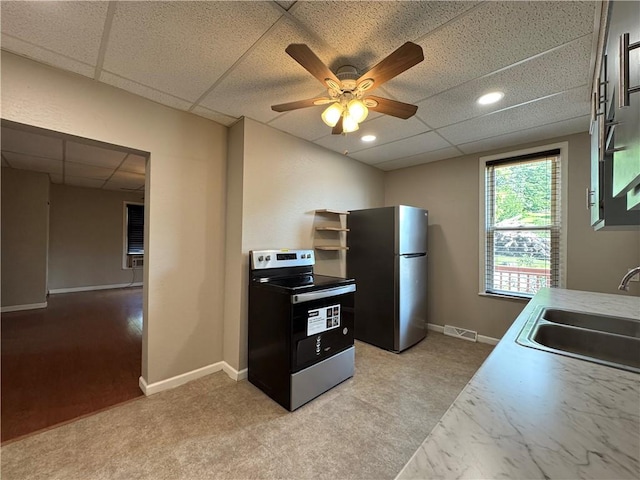 81 Baltimore St, Irwin, PA 15642 - kitchen with appliances with stainless steel finishes, a paneled ceiling, ceiling fan, light countertops, and light carpet