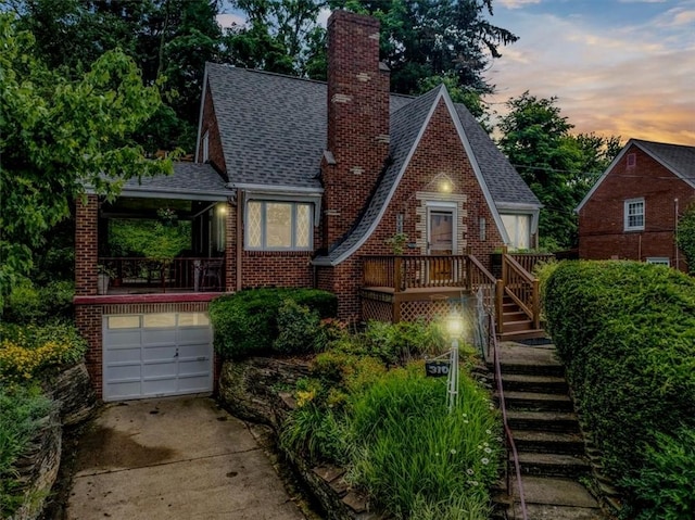 310 Glaser Ave, Bellevue, PA 15202 - tudor-style house with stairs, concrete driveway, a chimney, an attached garage, and brick siding
