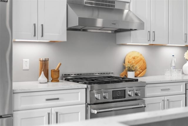 350 Oliver Ave Unit 1301/1401, Downtown Pgh, PA 15222 - kitchen with wall chimney exhaust hood, stainless steel appliances, white cabinets, and light stone counters