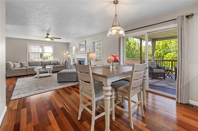 706 Williamsburg Ct, Cranberry Twp, PA 16066 - dining area with a glass covered fireplace, hardwood / wood-style floors, a ceiling fan, and a textured ceiling