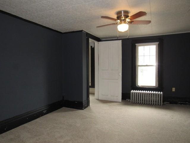 103 Memorial St, Dunbar, PA 15431 - spare room featuring radiator heating unit, a ceiling fan, and light colored carpet