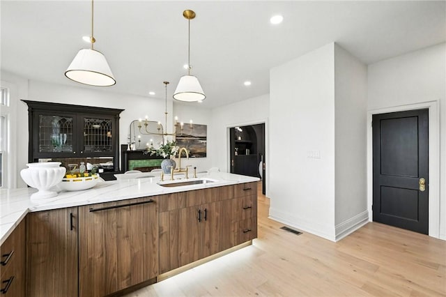 605 N Beatty, East Liberty, PA 15206 - kitchen with light wood-style flooring, decorative light fixtures, light stone counters, recessed lighting, and brown cabinetry