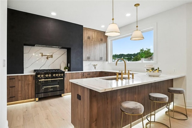 605 N Beatty, East Liberty, PA 15206 - kitchen featuring gas range, light wood-type flooring, light stone counters, a breakfast bar, and hanging light fixtures