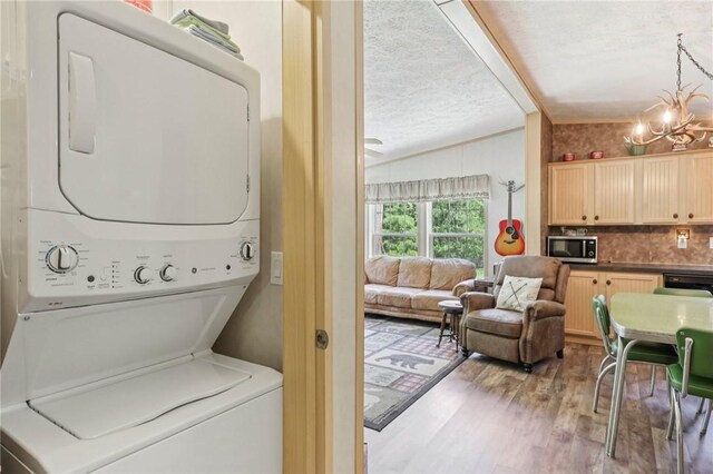 171 Fetter Ln, Ligonier Twp, PA 15658 - washroom featuring stacked washer / drying machine, a chandelier, wood finished floors, and a textured ceiling