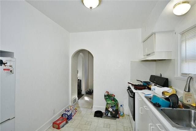 300 Sherman Ave, Dravosburg, PA 15034 - kitchen with gas range oven, freestanding refrigerator, arched walkways, under cabinet range hood, and white cabinets