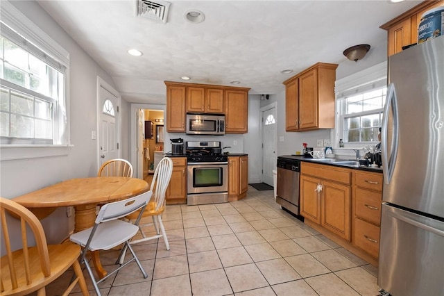 98 S 9th St, South Side, PA 15203 - kitchen with appliances with stainless steel finishes, light tile patterned flooring, dark countertops, brown cabinets, and healthy amount of natural light