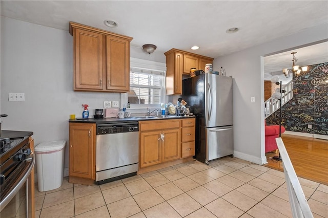 98 S 9th St, South Side, PA 15203 - kitchen with stainless steel appliances, dark countertops, a chandelier, light tile patterned floors, and brown cabinetry