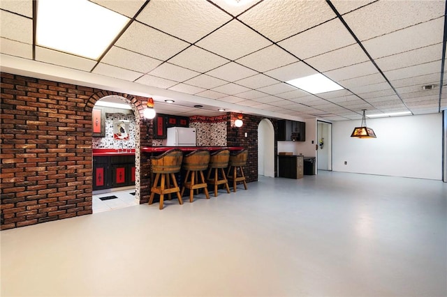 3215 Concord St, Neshannock Twp, PA 16105 - below grade area with freestanding refrigerator, bar area, brick wall, arched walkways, and a drop ceiling