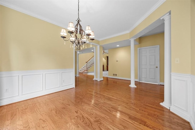 402 Providence Ct, Adams Twp, PA 16059 - unfurnished dining area featuring ornamental molding, light wood-style flooring, ornate columns, a wainscoted wall, and stairway