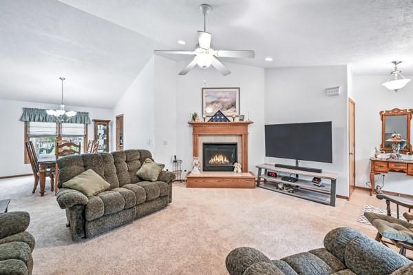3129 Saranac Dr, South Pymatuning Twp, PA 16150 - living room with carpet, a chandelier, a warm lit fireplace, ceiling fan, and lofted ceiling