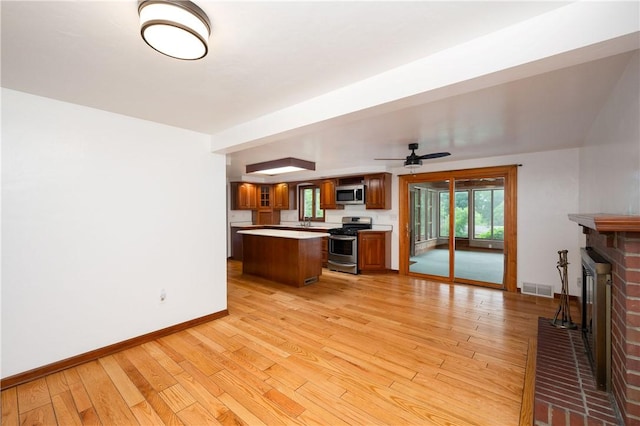 131 Windgate Dr, Marshall, PA 15090 - kitchen featuring stainless steel appliances, light countertops, light wood-style flooring, brown cabinets, and a brick fireplace