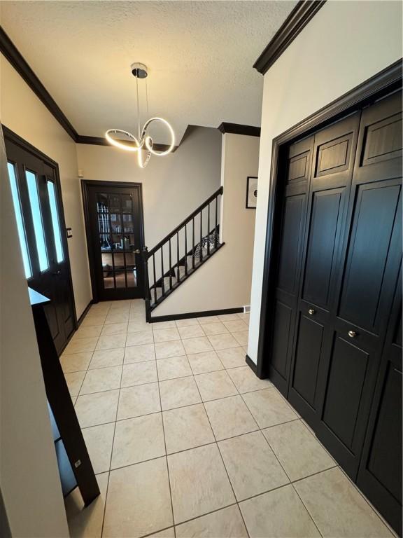 91 Celtic Ash Ct, Cranberry Twp, PA 16066 - foyer entrance featuring ornamental molding, light tile patterned flooring, a chandelier, and a textured ceiling