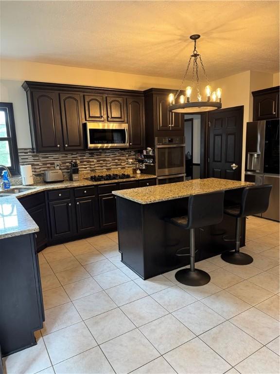 91 Celtic Ash Ct, Cranberry Twp, PA 16066 - kitchen featuring stainless steel appliances, a breakfast bar area, light stone counters, tasteful backsplash, and a kitchen island