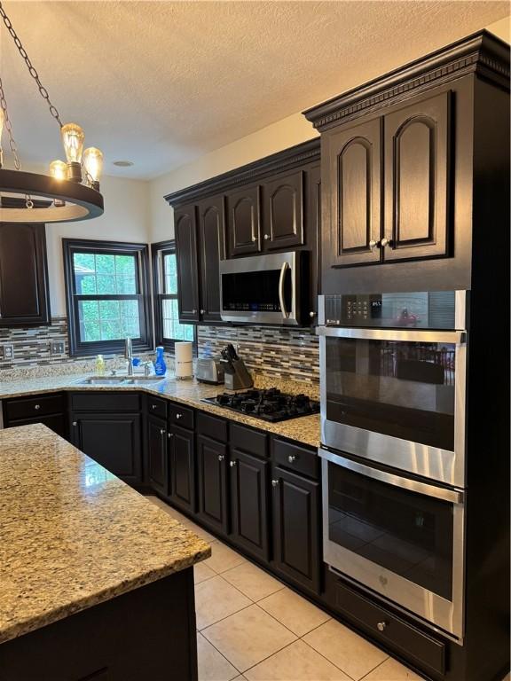 91 Celtic Ash Ct, Cranberry Twp, PA 16066 - kitchen with stainless steel appliances, tasteful backsplash, light stone countertops, light tile patterned floors, and a textured ceiling