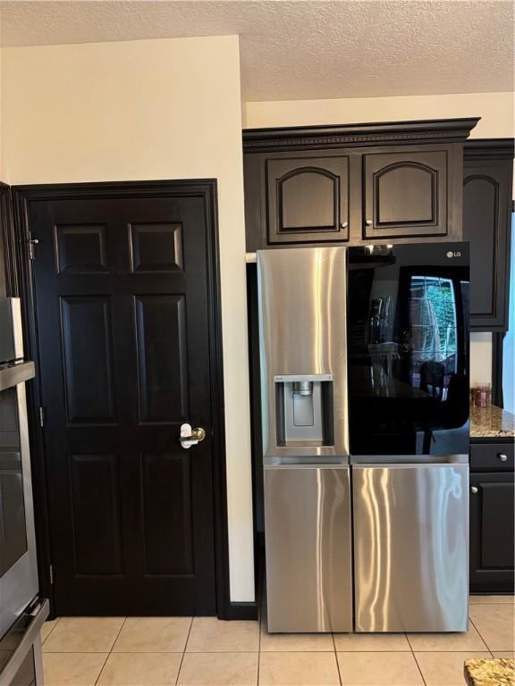 91 Celtic Ash Ct, Cranberry Twp, PA 16066 - kitchen featuring stainless steel appliances, light tile patterned floors, a textured ceiling, and stone counters