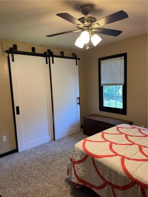 91 Celtic Ash Ct, Cranberry Twp, PA 16066 - bedroom with a barn door, carpet, a textured ceiling, and a ceiling fan