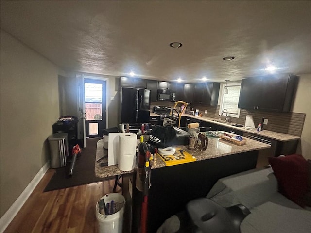 2814 Eccles St, South Side, PA 15210 - kitchen with black appliances, dark wood finished floors, a breakfast bar area, decorative backsplash, and a center island