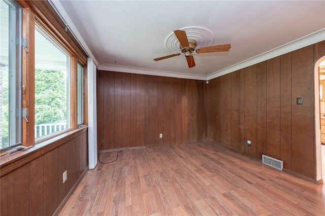246 Maple Dr, Monroeville, PA 15146 - empty room featuring a ceiling fan, light wood-type flooring, wood walls, crown molding, and arched walkways