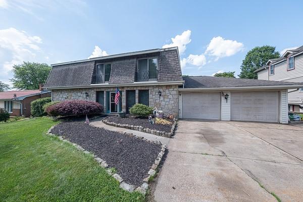 315 Pennsylvania Ave, Plum Boro, PA 15147 - view of front facade featuring stone siding, an attached garage, concrete driveway, a front yard, and mansard roof
