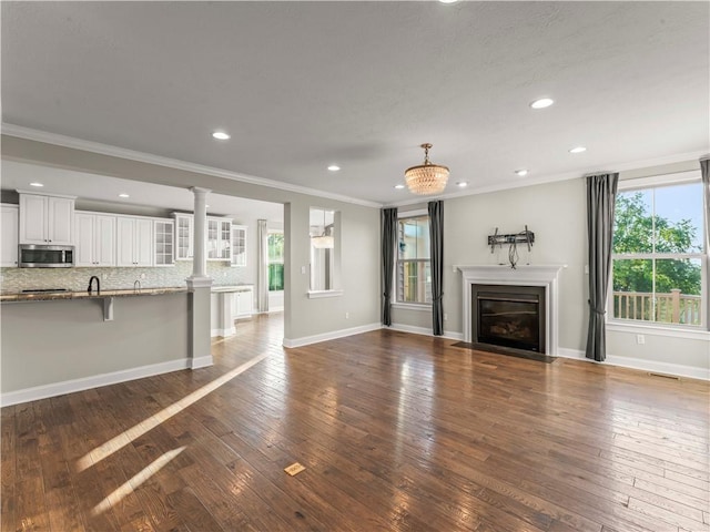 4402 Walnut Ridge Cir, South Fayette, PA 15057 - unfurnished living room featuring plenty of natural light, crown molding, dark wood-style floors, recessed lighting, and decorative columns