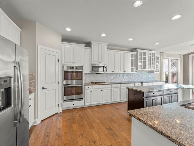 4402 Walnut Ridge Cir, South Fayette, PA 15057 - kitchen with appliances with stainless steel finishes, white cabinetry, tasteful backsplash, wood finished floors, and recessed lighting