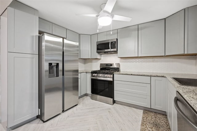 235 Ruth St, Plum Boro, PA 15239 - kitchen with appliances with stainless steel finishes, gray cabinets, a ceiling fan, and light stone countertops