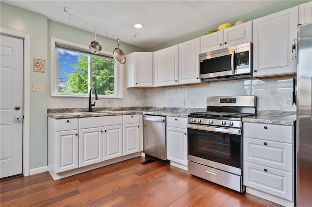 637 Bigelow St, Greenfield, PA 15207 - kitchen featuring appliances with stainless steel finishes, dark wood-style floors, white cabinetry, decorative backsplash, and light stone counters
