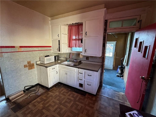 1413 Summit Ave, Monessen, PA 15062 - kitchen featuring white microwave, white cabinetry, dark countertops, a wainscoted wall, and tile walls
