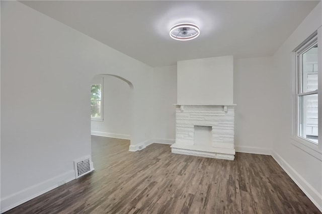 1311 Irwin St, Aliquippa, PA 15001 - unfurnished living room featuring dark wood-style flooring, a stone fireplace, and healthy amount of natural light