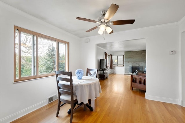 708 Washington St, Bentleyville, PA 15314 - dining space with light wood-type flooring, a ceiling fan, a fireplace, and crown molding