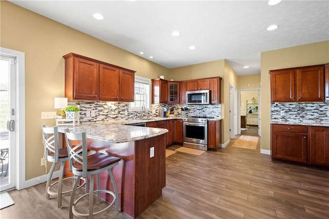 138 Crossridge Rd, Fallowfield, PA 15022 - kitchen featuring stainless steel appliances, a peninsula, light stone countertops, decorative backsplash, and glass insert cabinets