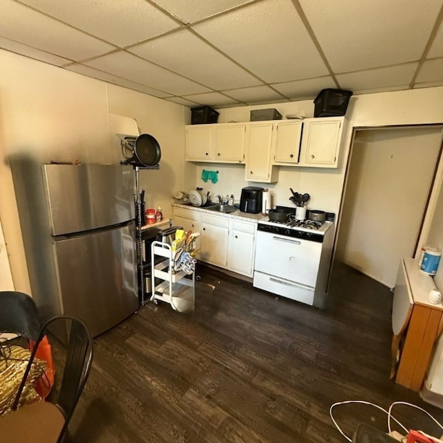 5837 Nicholson St, Squirrel Hill, PA 15217 - kitchen with freestanding refrigerator, a drop ceiling, white range with gas stovetop, dark wood-style floors, and white cabinetry