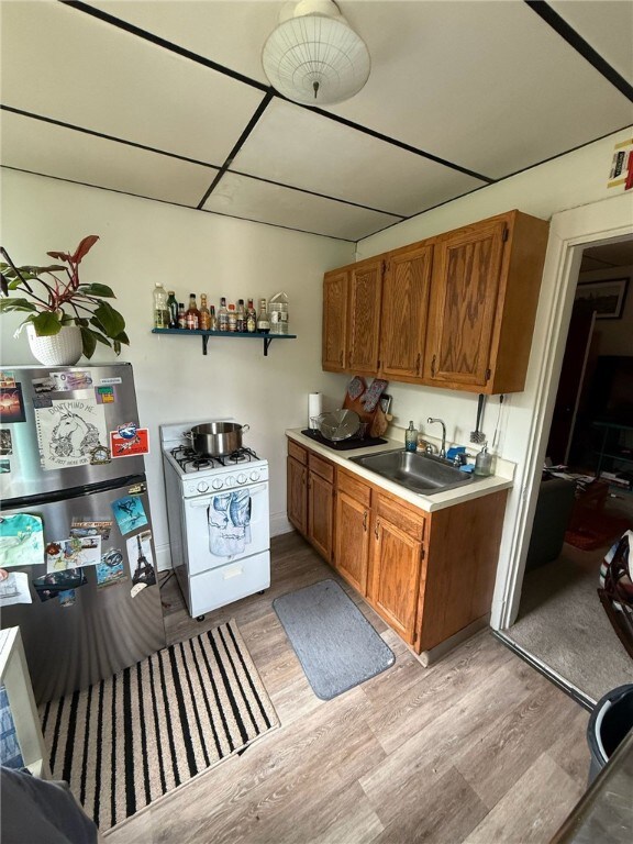 5837 Nicholson St, Squirrel Hill, PA 15217 - kitchen with white gas range oven, light wood-style floors, brown cabinets, light countertops, and freestanding refrigerator