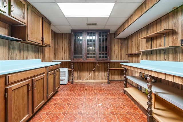 718 Twin Oak Dr, Penn Hills, PA 15235 - kitchen featuring open shelves, wooden walls, a drop ceiling, light countertops, and brown cabinetry
