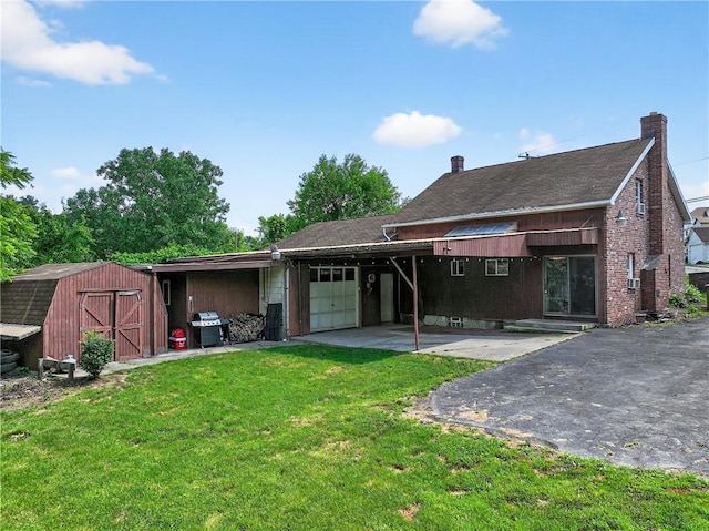 2509 Thomas St, Hempfield Twp, PA 15634 - rear view of house featuring a garage, asphalt driveway, a lawn, and a storage unit