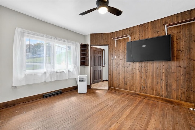 2509 Thomas St, Hempfield Twp, PA 15634 - unfurnished living room featuring wooden walls, a ceiling fan, and hardwood / wood-style flooring