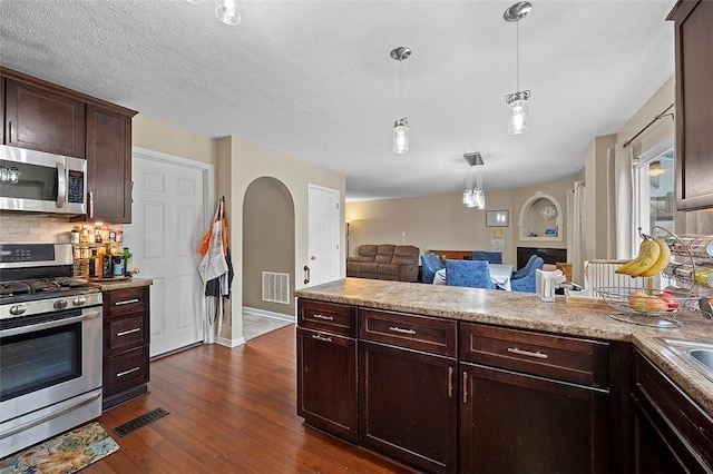 1071 Shawnee Ridge Dr, Cheswick, PA 15024 - kitchen featuring stainless steel appliances, open floor plan, arched walkways, dark wood-style floors, and light countertops