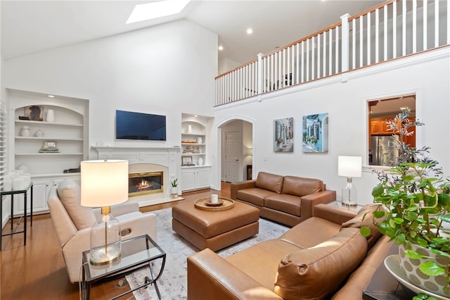 1413 Oak St, Oakmont, PA 15139 - living room featuring built in features, high vaulted ceiling, light wood-type flooring, a glass covered fireplace, and a skylight